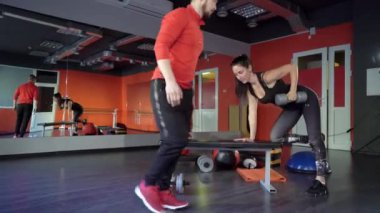 Genç sağlıklı sportif aktif şekil kız ile bir yakışıklı yararlı kişisel eğitmen yanında onu içinde the spor salonu.