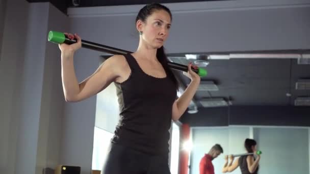Young healthy sporty active shape girl with a handsome helpful personal trainer next to her in the gym. — Stock Video