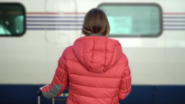Fiatal nő áll az állomáson a platform vár rá a vonat — Stock videók