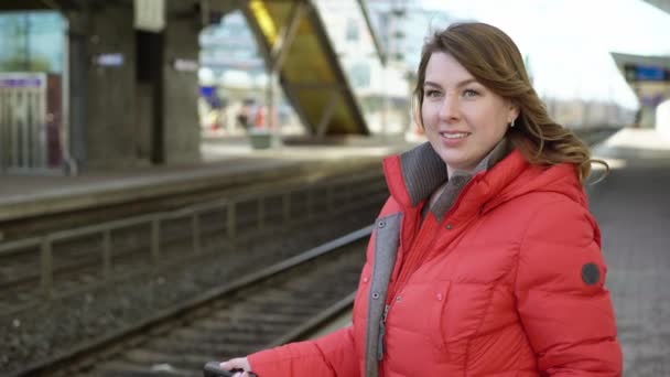 Tikkurila, フィンランド-3 月 24, 2019: 若い女性は、彼女の列車を待っている駅のプラットフォームに立っています — ストック動画