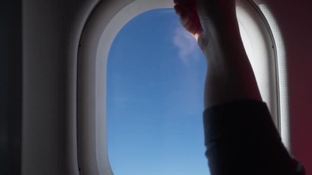 Silhouet van de vrouw de hand over het raam van het vliegtuig. Wolken en lucht gezien door raam van een vliegtuig, lucht vliegtuig — Stockvideo