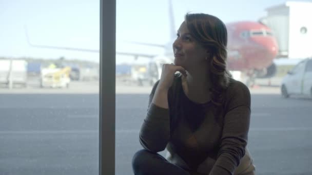 Νέα τουρίστρια στο αεροδρόμιο, κοιτάζοντας μέσα από το παράθυρο στο αεροπλάνο — Αρχείο Βίντεο