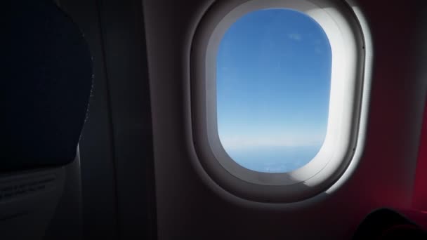 La silhouette d'une femme passe par la fenêtre de l'avion. Nuages et ciel vus à travers la fenêtre d'un avion, avion — Video