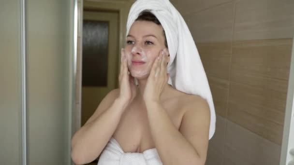 Nő takarítás mosás arcát a hab a fürdőszobában — Stock videók