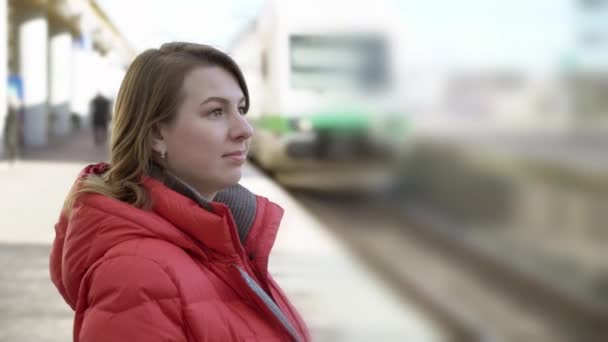 Wanita muda berdiri di stasiun platform menunggu keretanya — Stok Video