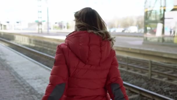 Wanita muda berjalan di platform stasiun menunggu keretanya — Stok Video