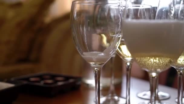 Verter champán de botella a vasos vacíos en la mesa — Vídeos de Stock