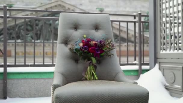 Свадебный свадебный букет цветов на стуле на террасе в зимний снежный день — стоковое видео