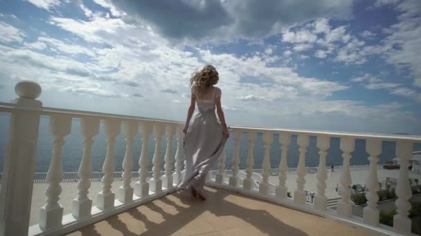 Молодая блондинка в нижнем белье позирует на террасе с видом на море — стоковое видео
