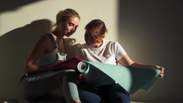 Due ragazze al cantiere discutendo e scegliendo sfondi per il loro appartamento — Video Stock