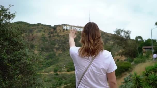 Fiatal nő sétál a Hollywood felirat közelében — Stock videók