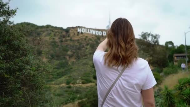 Mujer joven caminando cerca de Hollywood signo — Vídeos de Stock