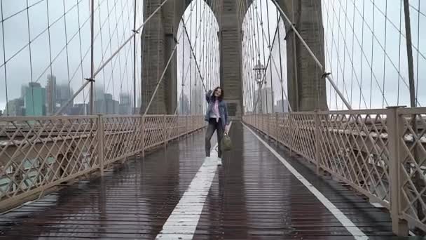 Ung kvinna går vid Brooklyn Bridge — Stockvideo