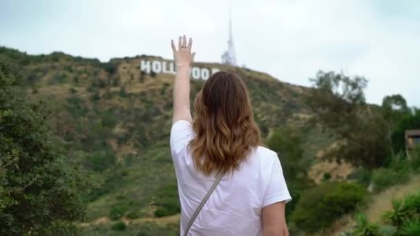 Mujer joven caminando cerca de Hollywood signo — Vídeos de Stock