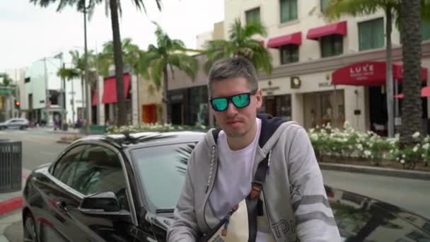 Лос-Анджелес, США-9 травня 2019: людина сидить на капоті розкішного автомобіля — стокове відео