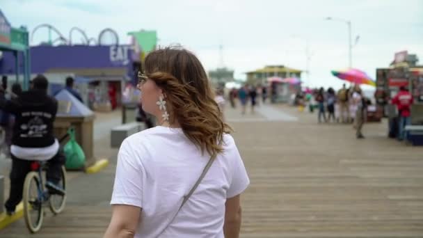 Młoda kobieta spacerująca po molo Santa Monica — Wideo stockowe