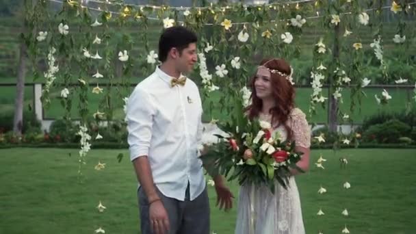 Novia y novio en la ceremonia de boda. Jardín tropical por la noche. Preciosa pareja de recién casados — Vídeos de Stock