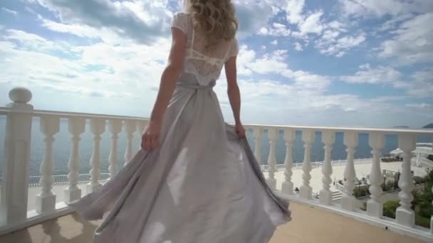 Fiatal, szőke nő, a tengerre néző teraszon pózol fehérnemű — Stock videók