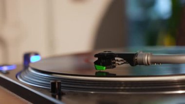 Stylus ile donatılmış, rahat bir ortamda vinil plak çalan bir turntable kolunun ayrıntılı görüntüsü.