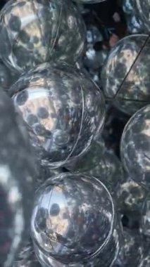 Parlak metalik toplardan oluşan büyüleyici bir küme etrafındaki ışıkları ve çevreyi güzelce yansıtıyor.