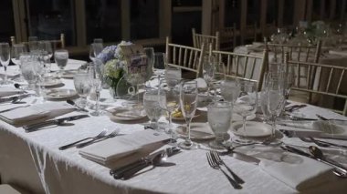 Zarif cam takımları, güzel çatal bıçakları ve büyüleyici çiçek dekoru olan güzel bir yemek masası.