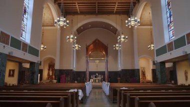 Kilisenin içi nefes kesici bir manzaraya sahip, etkileyici ahşap kirişler ve renkli camlar var.