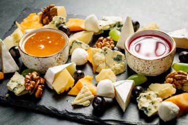 Siyah bir masanın üzerinde peynir tabağı. Bir tabakta peynir birçok türde