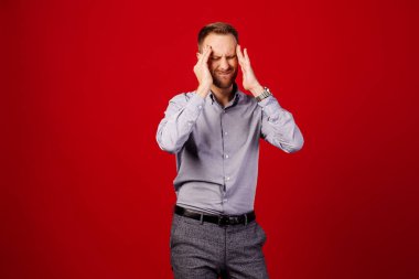 kırmızı arka plan üzerinde adam şiddetli baş ağrısı muzdarip, tapınaklara parmak basarak, ağrı gidermek için gözleri kapatma