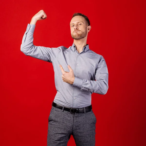 Mężczyzna z bicepsami na czerwonym tle. Ludzie i emocje — Zdjęcie stockowe