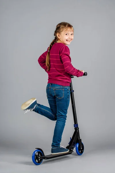 girl with black scooter over gray background
