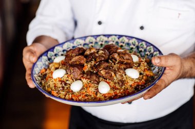 sebze, et ile özbek pilavı ulusal çanak tutan el 