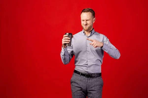 man with cup of coffee over red background with angry face, nega