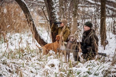 karlı kış orman içinde tüfeklerle iki avcı. 