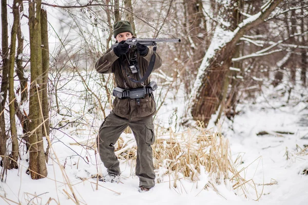 Κυνηγός αρσενικό στο καμουφλάζ, οπλισμένος με ένα τουφέκι, στέκεται σε μια sno — Φωτογραφία Αρχείου