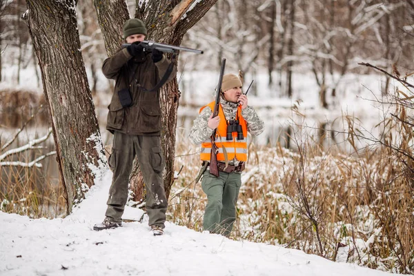 Κυνηγοί οπλισμένοι με τουφέκι, στέκονται σε ένα χιονισμένο χειμερινό δάσος — Φωτογραφία Αρχείου