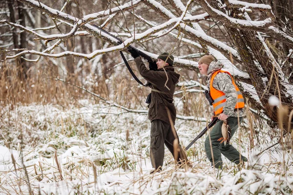 Manliga jägare beväpnade med ett gevär, stående i en snöig vinter fore — Stockfoto