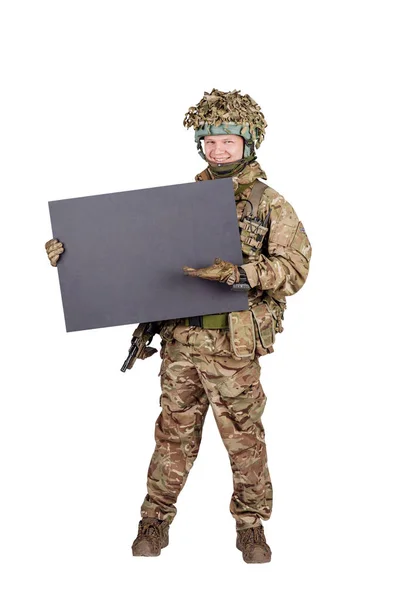 Soldier with rifle holding white panel with space for text on wh — Stock Photo, Image