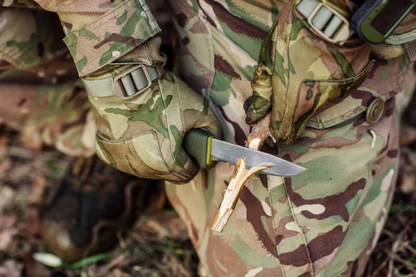 ナイフを持った兵士が木の棒を切った. — ストック写真