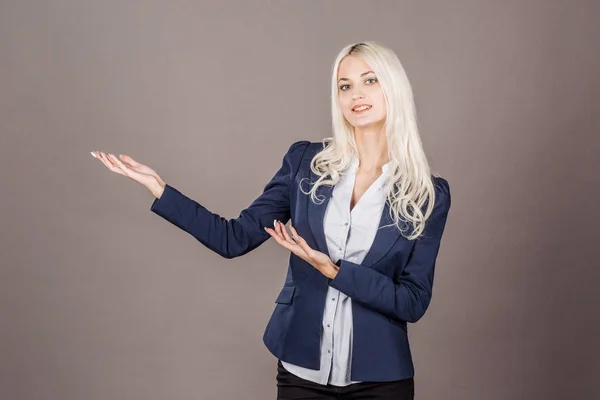 Smilende kvinne viser noe på grå bakgrunn. livsstil og – stockfoto