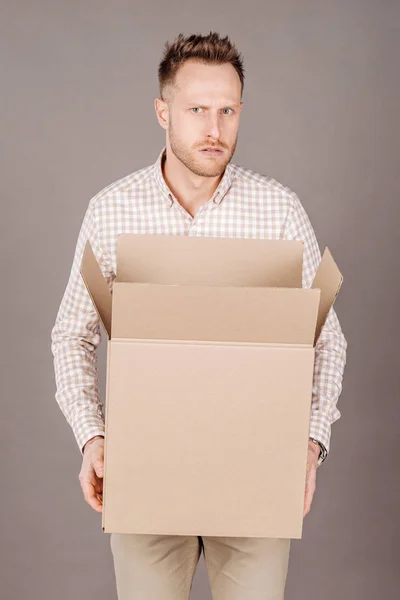 Молодой человек, держа большую упаковочную коробку и улыбаясь — стоковое фото