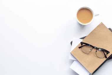 Üst görünüm çalışma alanı, kahve fincanı ve beyaz masa arkaplanındaki defter