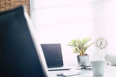 Defter üzerinde kahve ile sabah güneş ışığı, çalışma alanı içinde beyaz masa üstünde laptop