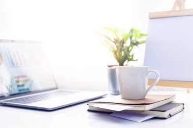 Defter üzerinde kahve ile sabah güneş ışığı, çalışma alanı içinde beyaz masa üstünde laptop