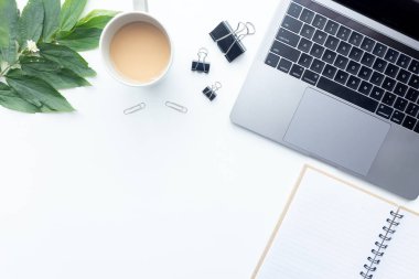 Üstten görünüm çalışma alanı, arka plan üzerinde kahve Kupası ve ofis donanımları ile beyaz masa üstünde laptop