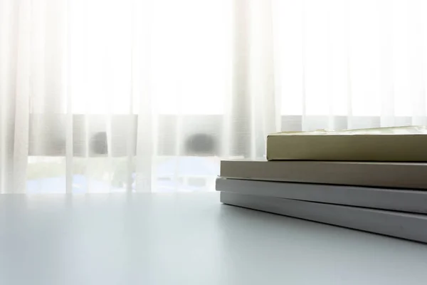 日差しのない窓の横の白いテーブルの上の本 — ストック写真