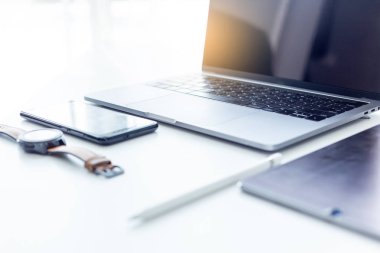 Masaüstü bilgisayar ofisi olan çalışma alanını kapat, güneş ışığı olan beyaz masadaki laptopu kapat