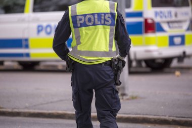 Yansıtıcı yelek ve silah ile İsveç polis memuru