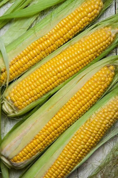 Taze mısır koçanı üzerinde rustik ahşap masa, yakın çekim. Tatlı Mısır kulakları arka plan
