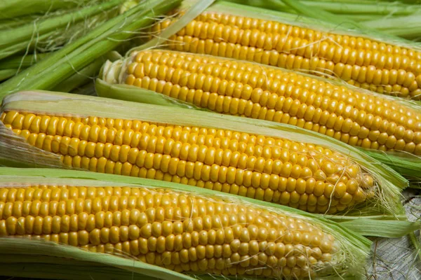 Fresh corn on cobs on rustic wooden table, close up. Sweet corn ears background