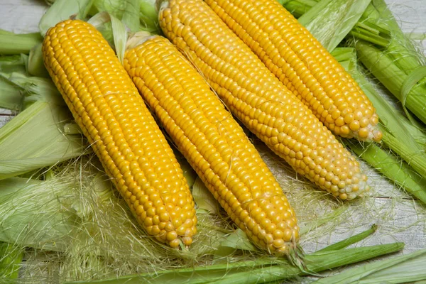 Fresh corn on cobs on rustic wooden table, close up. Sweet corn ears background